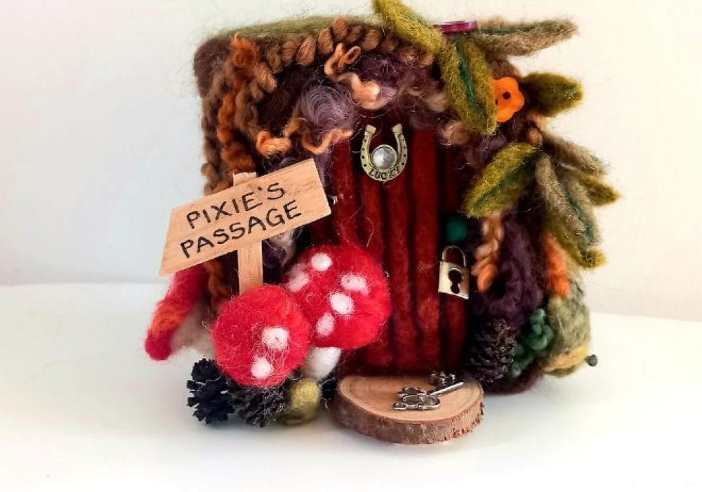 An Image of a needle felt wooden door with mushroom and leaves decorating its boarder, these are also needle felted.