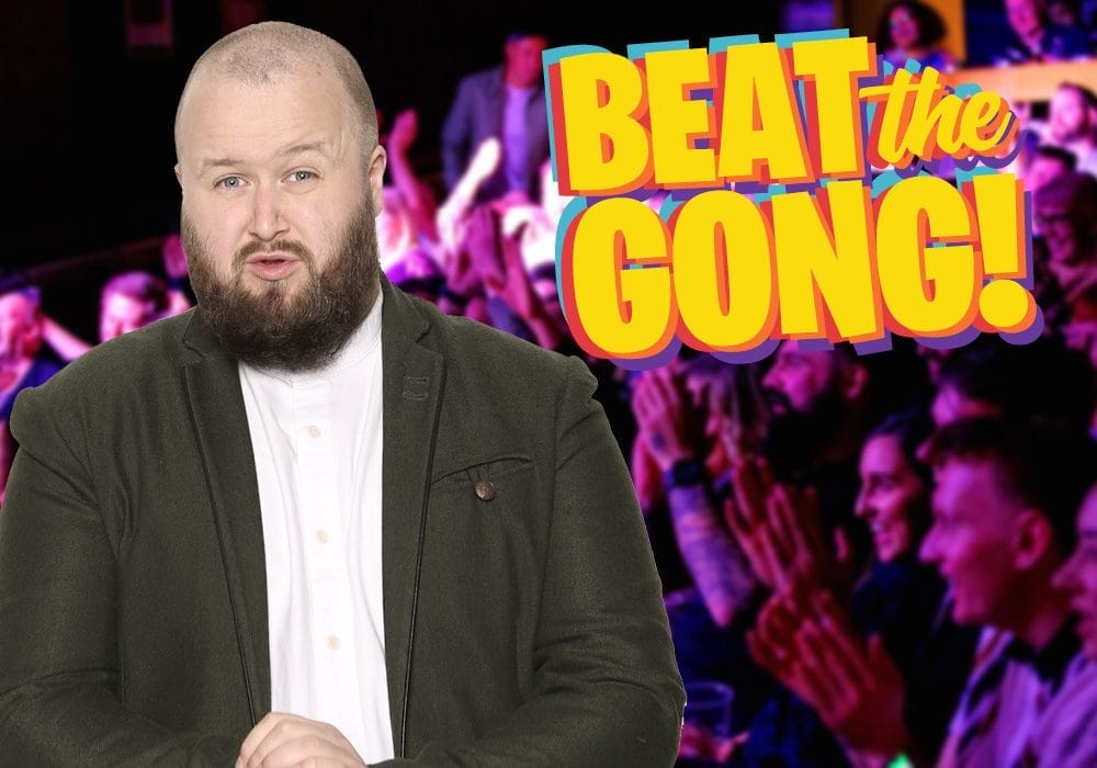Comedian Freddy Quinne standing to the right of an animated Beat the Gong logo.