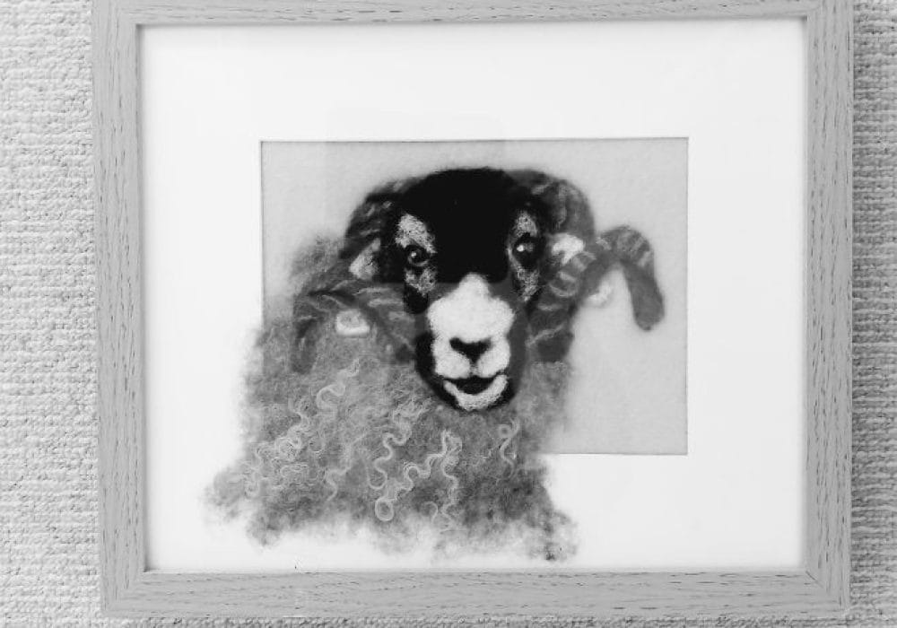 a black and white image of a needle felt ram in a frame