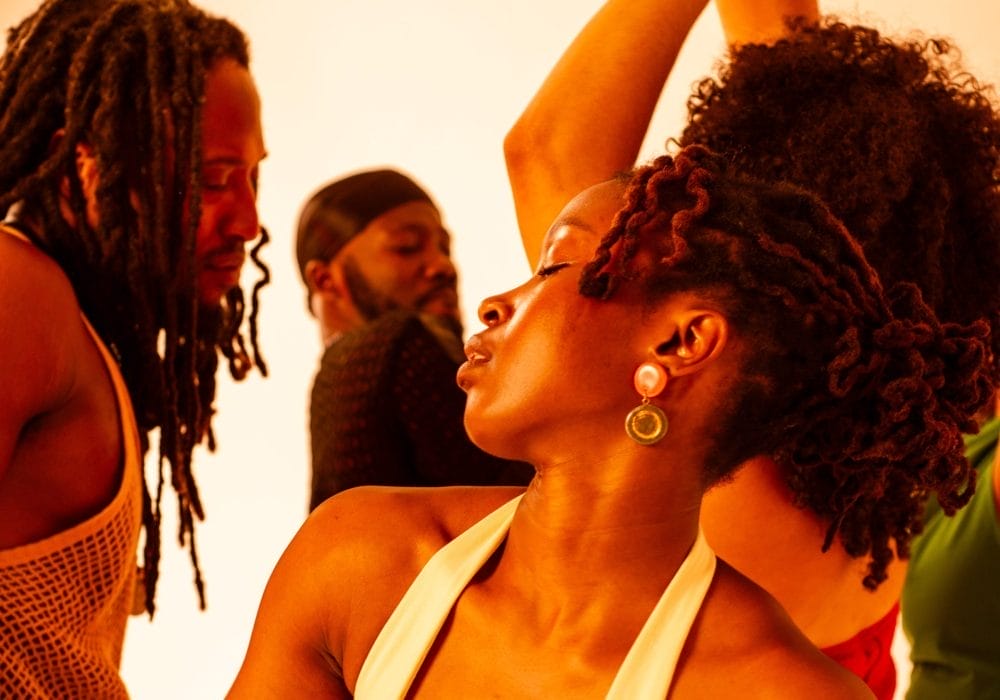 A vibrant, warm-toned photograph showing people in what appears to be a joyful, celebratory moment. The golden lighting creates a beautiful atmosphere, and everyone looks happy and engaged with each other.
