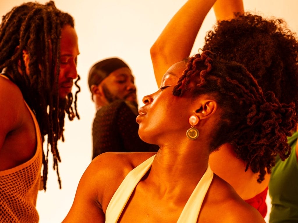 A vibrant, warm-toned photograph showing people in what appears to be a joyful, celebratory moment. The golden lighting creates a beautiful atmosphere, and everyone looks happy and engaged with each other.