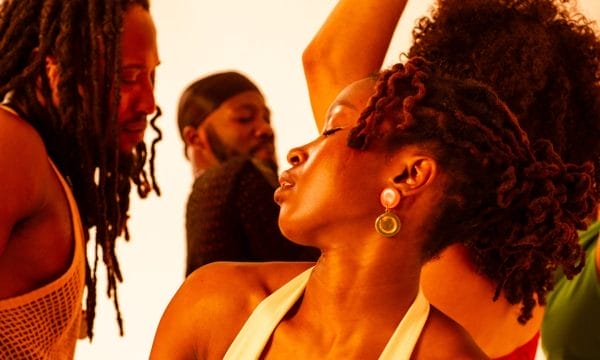 A vibrant, warm-toned photograph showing people in what appears to be a joyful, celebratory moment. The golden lighting creates a beautiful atmosphere, and everyone looks happy and engaged with each other.