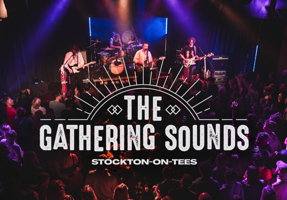 Live music venue photograph showing a band performing on stage with dramatic purple and blue stage lighting. The stage features a four-piece band with guitars, drums, and other instruments, with atmospheric smoke effects. In the foreground, a large crowd of audience members can be seen enjoying the performance, many with raised hands. Overlaid on the image is 'The Gathering Sounds' logo in large white distressed text with a decorative sunburst design above it, and 'Stockton-on-Tees' underneath. The scene captures the energetic atmosphere of a live music event in an intimate venue setting
