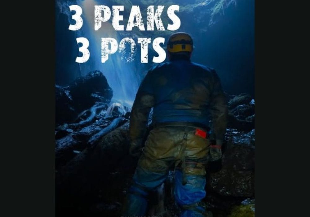 An image of a man in a hard hat and other caving gear, walking towards a cave opening. In the top of the screen there is a white title saying '3 peaks 3 pots'