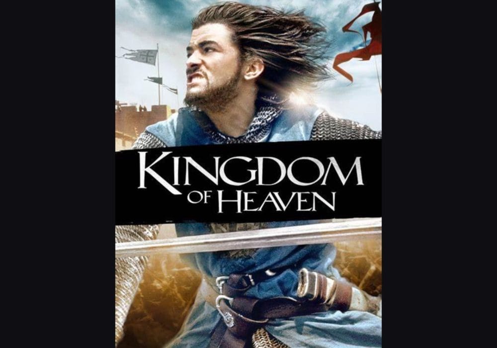 An image of a man with long hair and a beard wearing chain mail and holding a sword. In the background there is sky and flags waving. The text reads 'Kingdom of Heaven'
