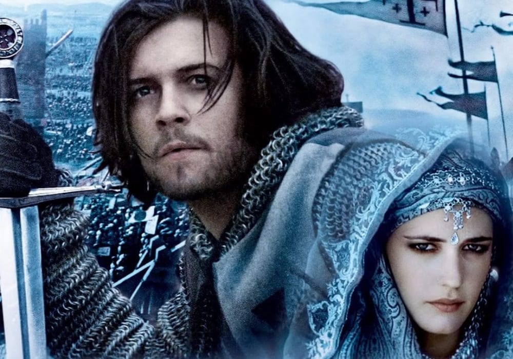 The image shows two people in medieval attire with a backdrop of what looks like a battlefield or city with an army. The scene depicts characters in historical costume with chainmail, a sword, and ornate Middle Eastern-inspired dress, set against what appears to be a medieval battlefield or fortress setting.