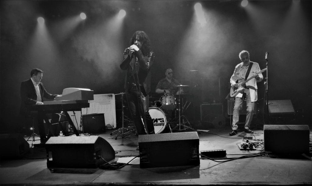 A black and white image of a band performing on stage.