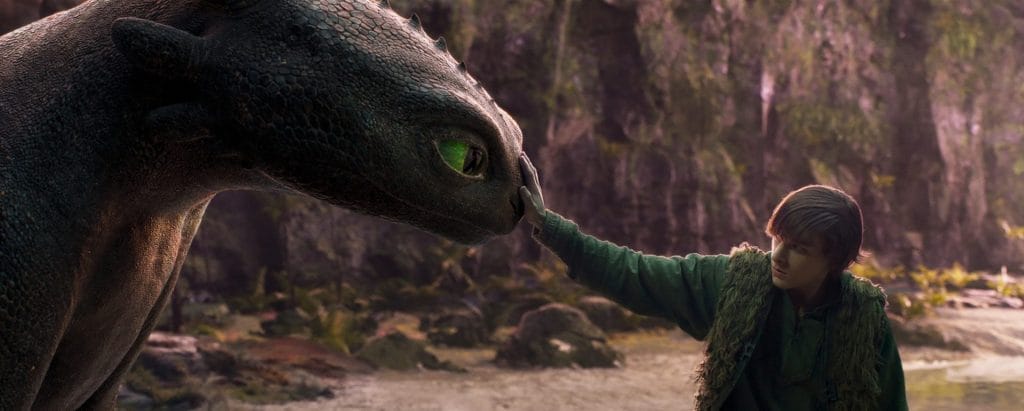 Image of a young boy stroking a dragon's nose.