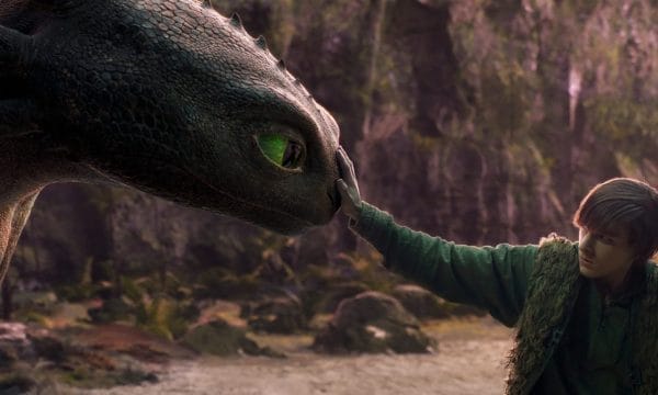 Image of a young boy stroking a dragon's nose.