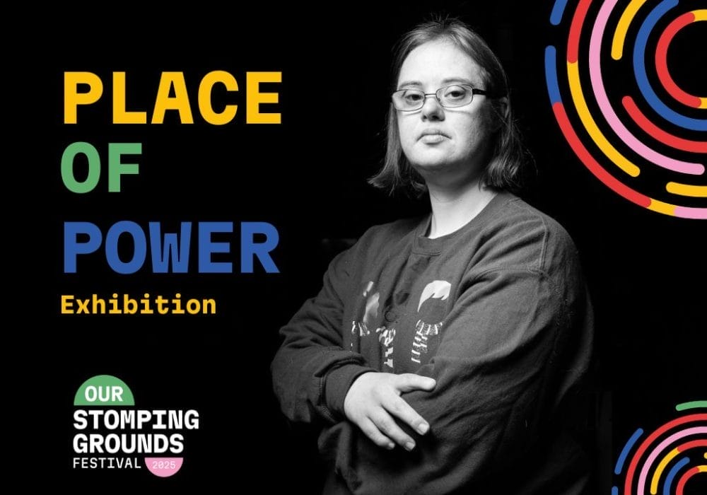 A monochrome image of a young person wearing glasses, arms folded. They have a neutral expression on their face.