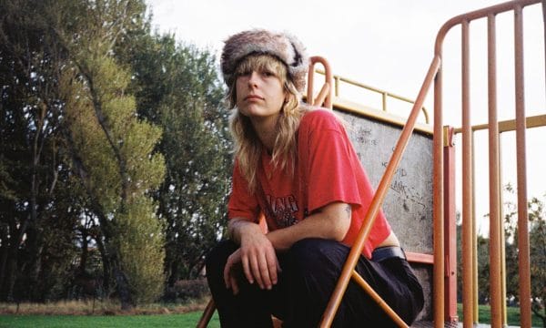 Melanie sits on steps to a play area in a park seating looking at you