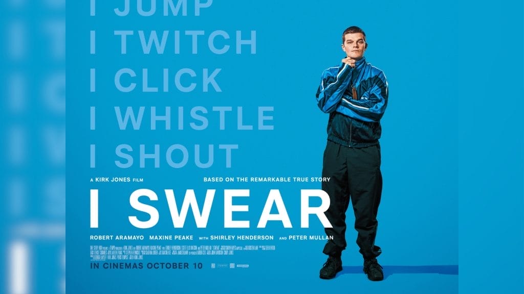 A young man with short hair wearing a blue and black tracksuit stands confidently resting a closed hand on his chin