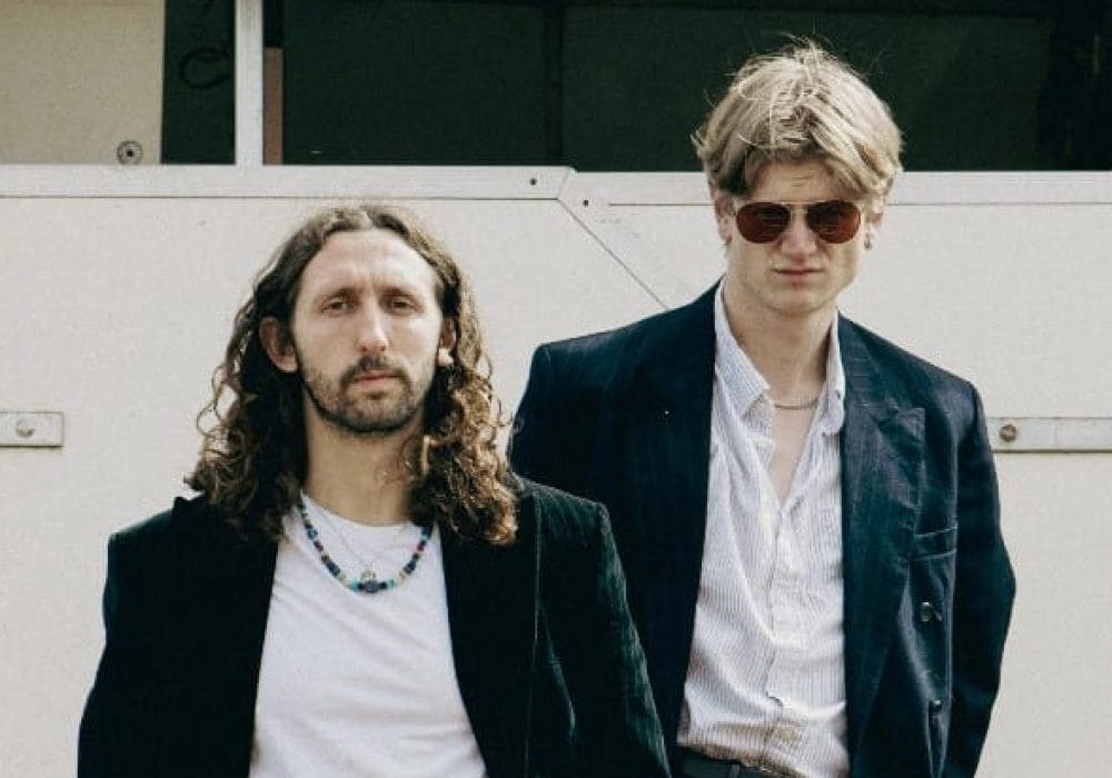 Two male musicians wearing dark jackets looking moody