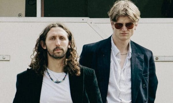 Two male musicians wearing dark jackets looking moody
