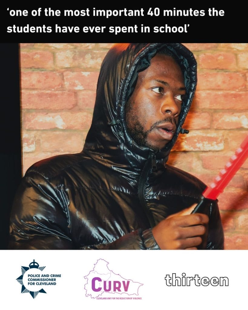 A person in a shiny black jacket holding a red knife poses in front of a brick wall, highlighting a pivotal moment.