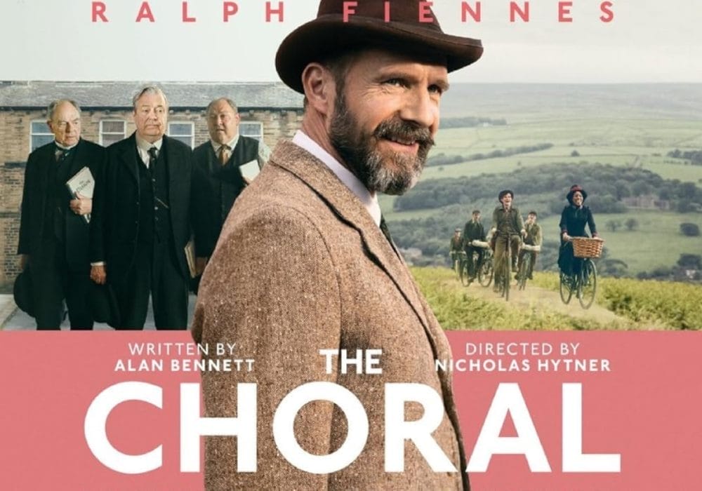 A man dressed in 1900's clothing surrounded by Yorkshire country side and choir of people in the background