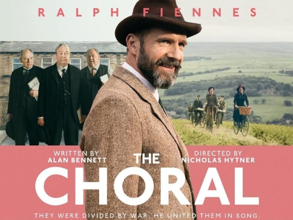 A man dressed in 1900's clothing surrounded by Yorkshire country side and choir of people in the background