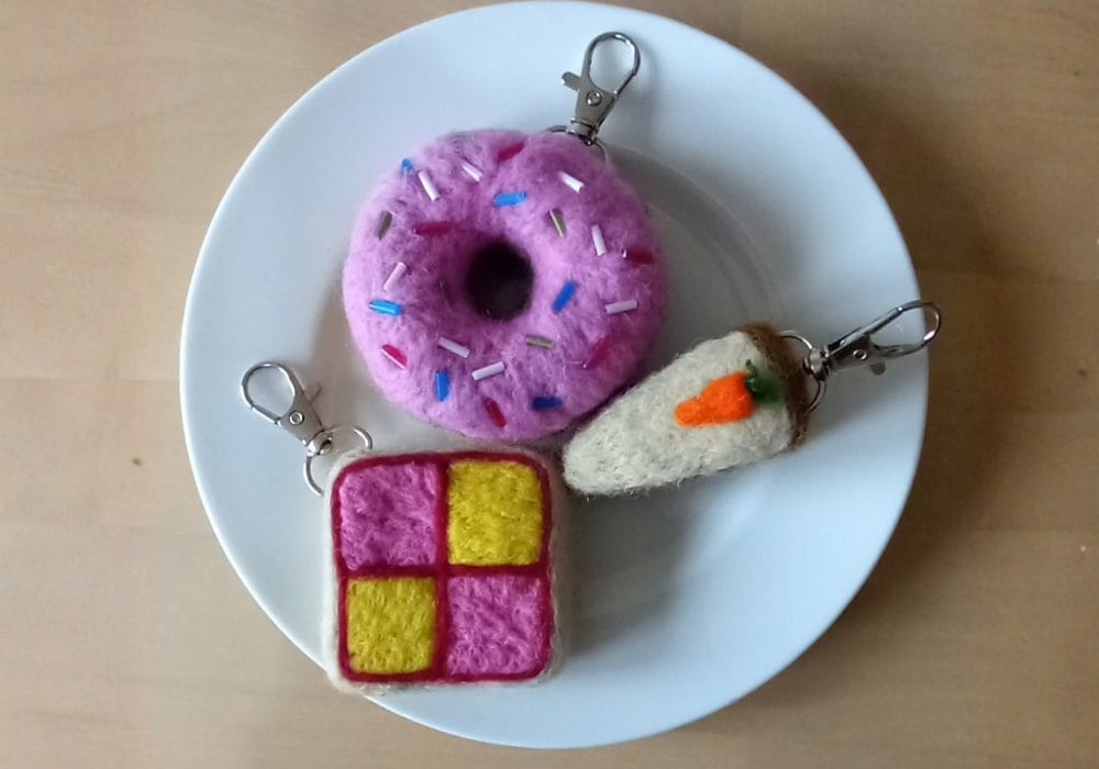 A white plate with 3 food items that have been made out of felt