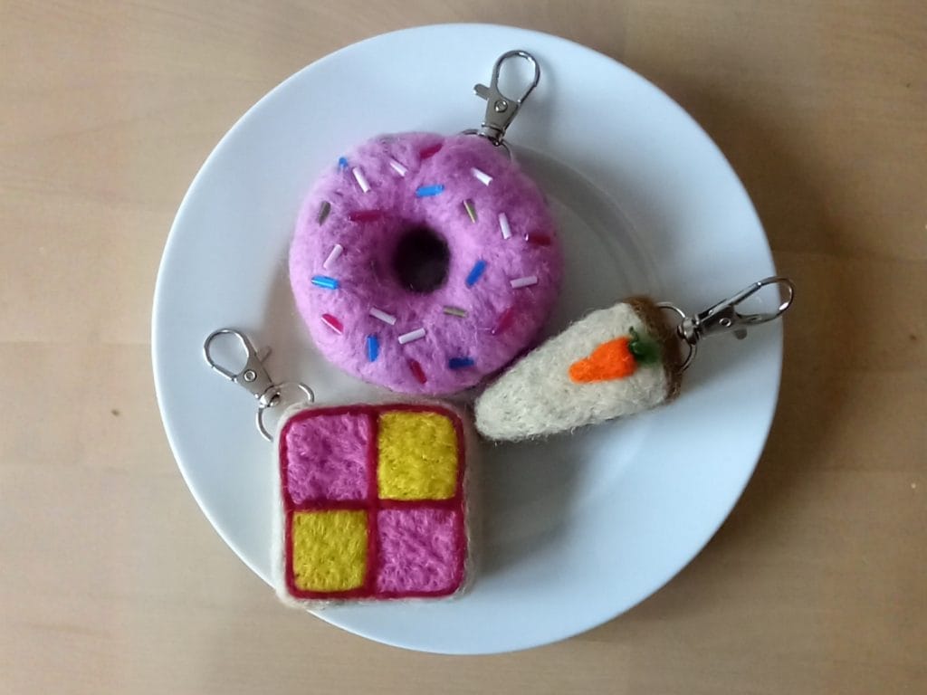 A white plate with 3 food items that have been made out of felt
