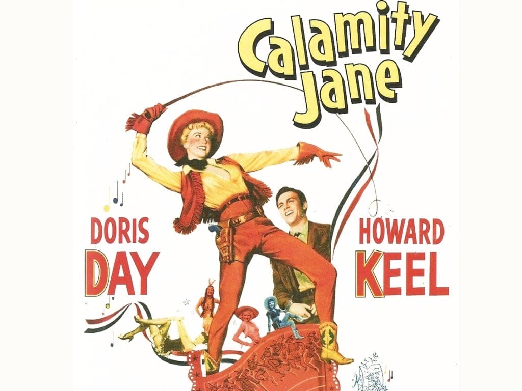 A woman dressed as a cowboy holding a whip