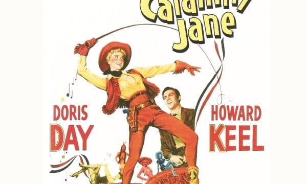 A woman dressed as a cowboy holding a whip