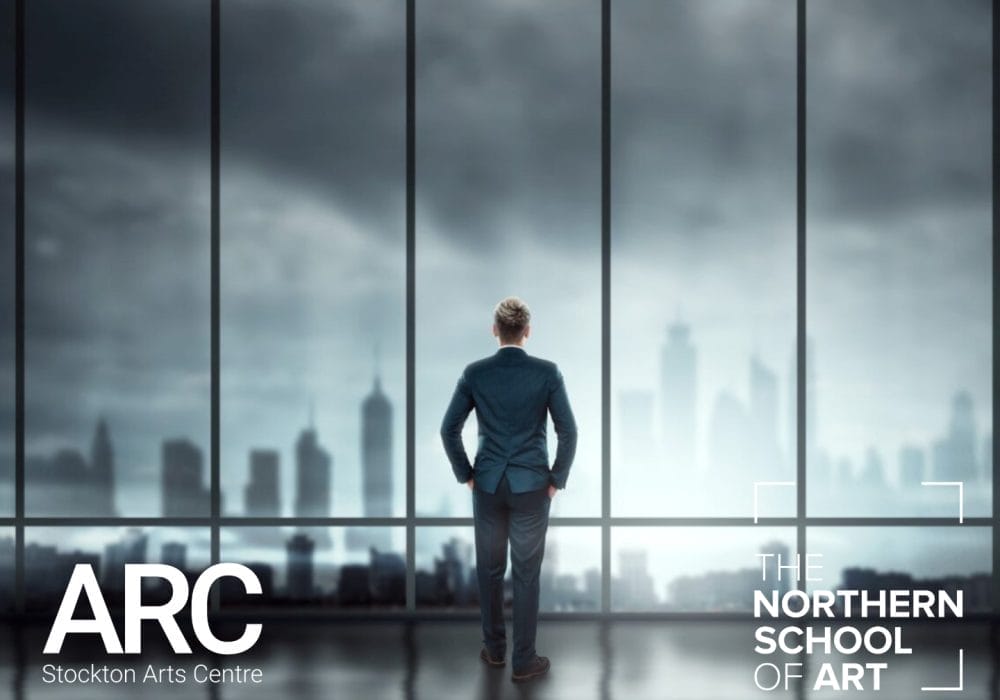 A man wearing a suit standing in front of a large window looking out at a cityscape